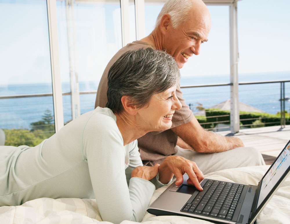 Senior couple looking at laptop in bed