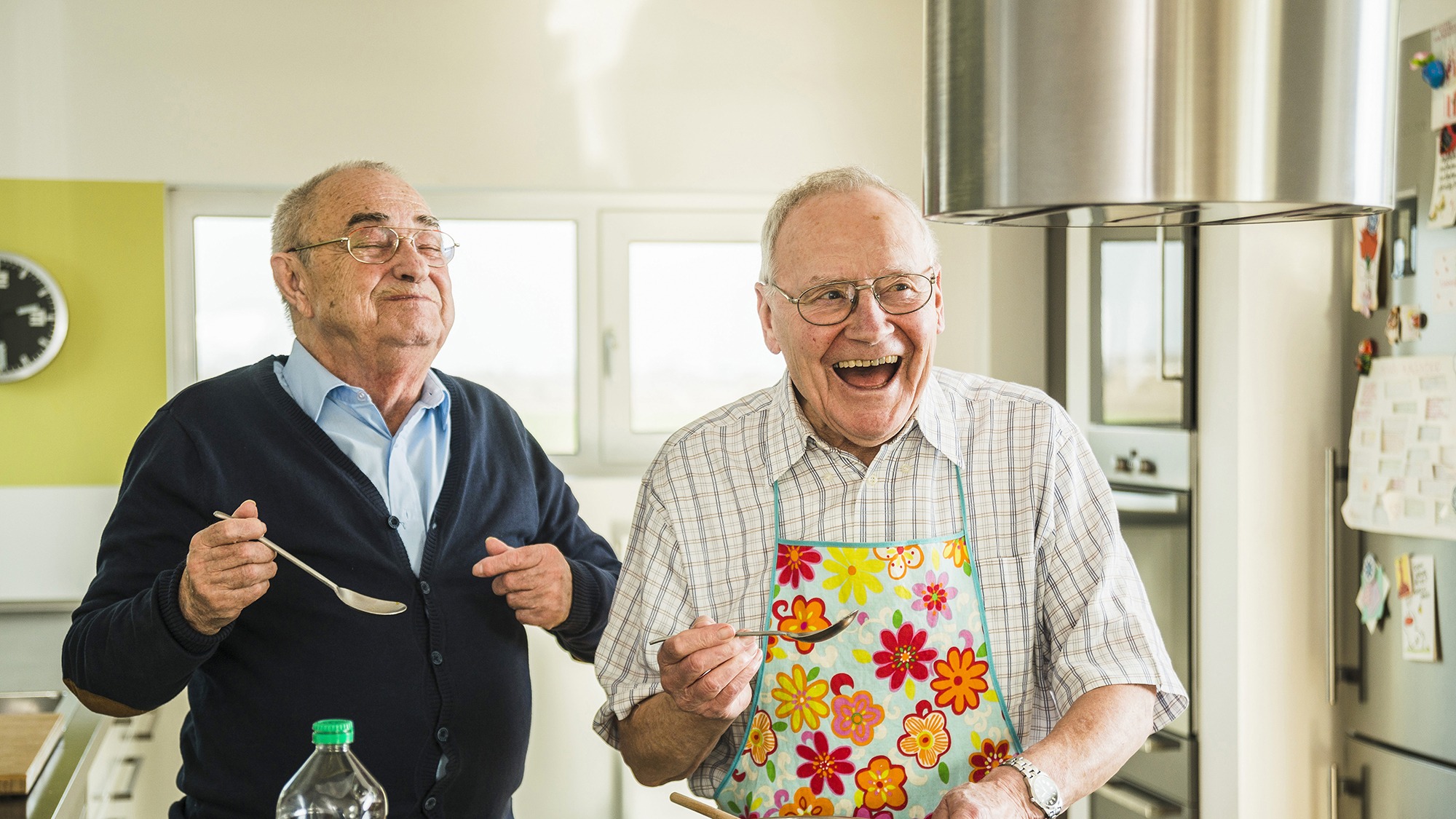 Two happy senior friends cooking in kitchen