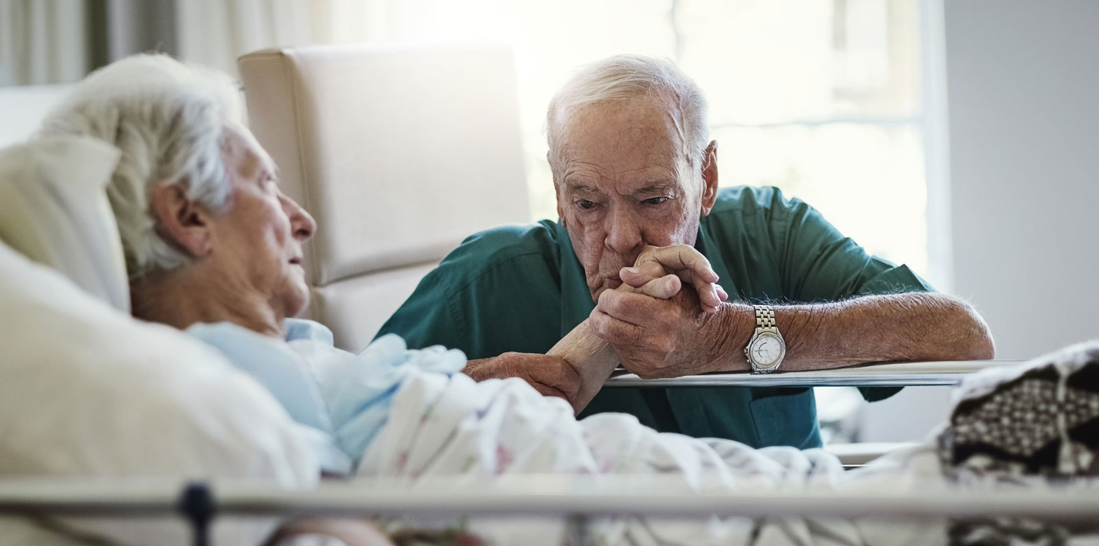 Senior man kissing hospitalised wifes hand
